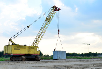 Crawler crane on the construction site for loading and unloading and construction works. Heavy industrial machinery on the background of a sunset