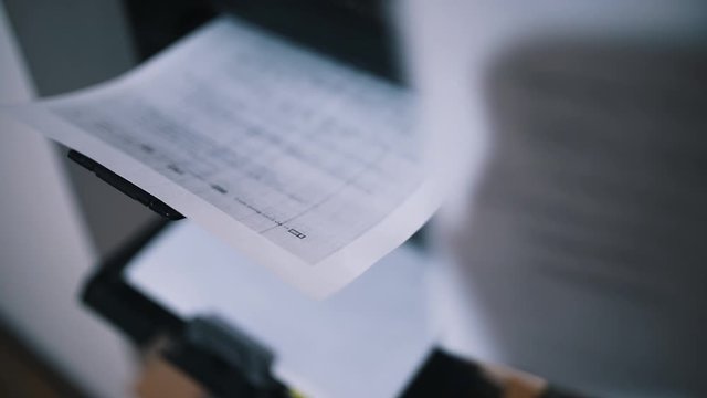 Woman office worker tacking printed document or papers from laser printer.