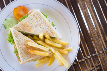 Top view of sandwich toast with lettuce, ham, cheese and tomato with french fried.