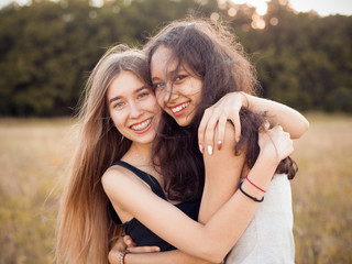 Two happy girls hugging outdoors under sunlight. Best friends