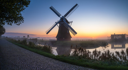 Windmill during a foggy, autumn sunrise in the Dutch countryside. Krimstermolen, Zuidwolde.