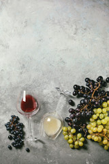 Traditional New european low alcohol red and white wine Federweisser or Neuer Wein, Burcak, Vin bourru in lying glasses with black and green grapes over grey concrete background. Flat lay, space