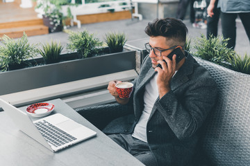 Young beard man using laptop on office, freelance work, outdoor close up hipster portrait, brutal, guy listening music on earphones, make photo and video, production, Bali, watch OS