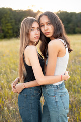 Fototapeta premium Two beautiful young women hugging on the field under sunlight, Best friends