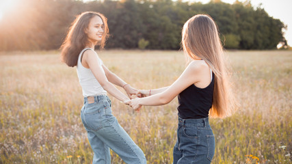 Two happy young women having fun on the autumn field at evening