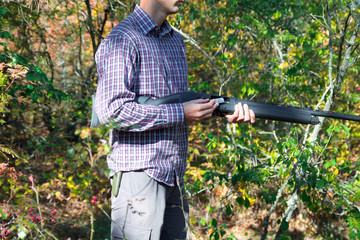 male with semi-automated shotgun in the autumn forest