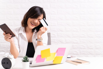 Happy woman use smart phone and credit card at office