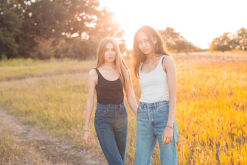 Two young women walking outdoors at sunset. Best friends