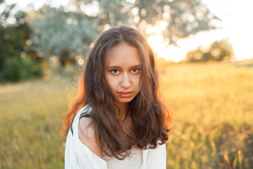 Naklejka premium Beautiful young woman in white shirt posing outdoors at sunset