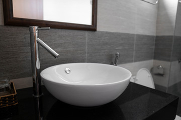 Bathroom interior with white round sink and chrome faucet in a modern bathroom.
