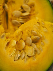 A closeup of a bright yellow pumpkin slice with seeds