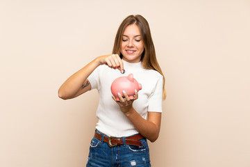 Young blonde woman over isolated background holding a big piggybank