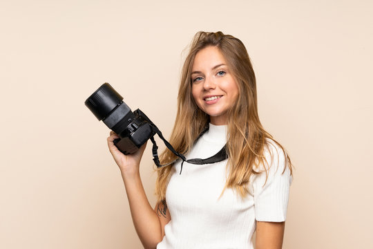 Young blonde woman over isolated background with a professional camera