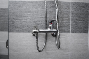 Modern designer tap and shower in bathroom. Closeup of chrome shower, faucet, in the bathroom covered decorative ceramic. Mixer cold hot water.