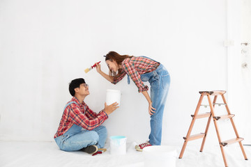 Fototapeta na wymiar young asian couple in yom-bear and plaids shirts in concept couple help painting a new color the room renovation