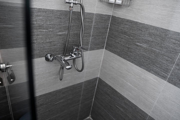 Modern designer tap and shower in bathroom. Closeup of chrome shower, faucet, in the bathroom...