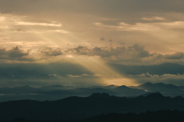 Beautiful sunrise in the mountains. Landscape with sun shining through orange clouds in Myanmar