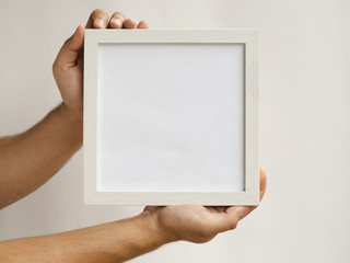 Close-up hands holding a frame mock-up