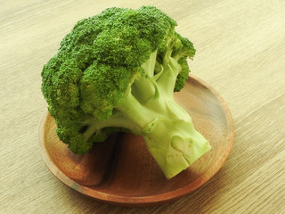 High angle view of healthy green raw broccoli on wooden plate isolated on wooden background....