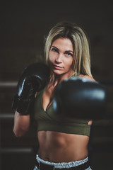 Attractive female boxer is making her strong punch while posing for photographer.