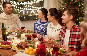 holidays and celebration concept - happy friends having christmas dinner at home and eating