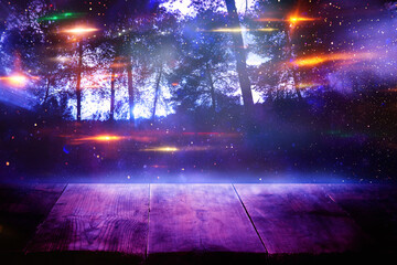 Fototapeta na wymiar Holidays Halloween concept. Empty rustic table in front of scary and misty night sky and forest background. Ready for product display montage