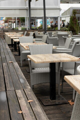 Autumn story: tables and chairs of open street cafes empty and w