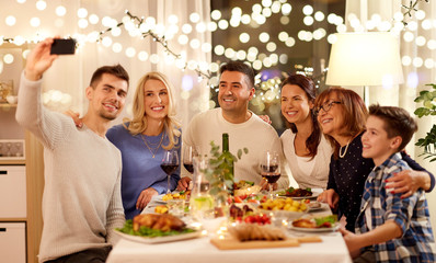celebration, holidays and people concept - happy family having dinner party at home and taking selfie by smartphone