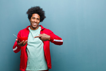 young black man with a breakfast bowl against blue grunge wall