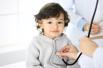 Doctor examining a child patient by stethoscope. Cute arab boy at physician appointment. Medicine and healthcare concept