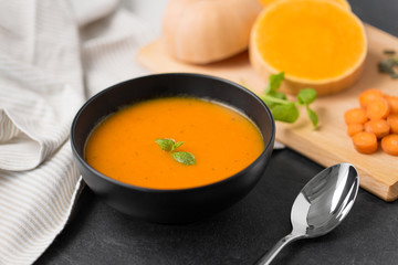 food, new nordic cuisine, culinary and cooking concept - close up of vegetable pumpkin cream soup in bowl and spoon on stone table