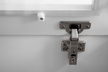 Chromic cabinet swing door hinge, build in furniture fittings hardware for wardrobe, cupboard or kitchen. Closeup of furniture cabinet modern clip hinge.