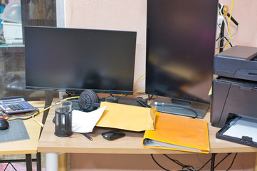 Messy workplace table with PC, monitor and laptop on it.