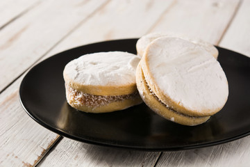 Traditional Argentinian alfajores with dulce de leche and sugar on wooden table
