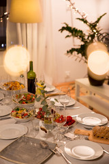 celebration, holidays, catering and eating concept - table served with plates, wine glasses and food for home dinner party