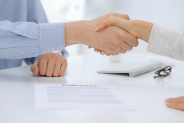 Business people shaking hands at meeting or negotiation after contract discussing. Businessman and woman handshake at office while sitting at the desk. Success concept