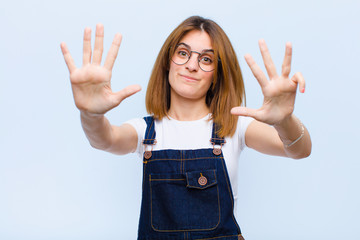 young pretty woman smiling and looking friendly, showing number nine or ninth with hand forward,...