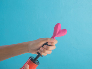 Hand pumping small heart shape balloon.In love concept