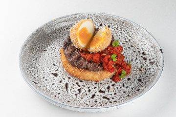Marbled beef steak with deep fried egg, chili sauce and potato hash brown isolated on white flat lay