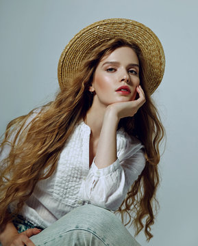 Beautiful romantic young girl in a straw hat and a white shirt thoughtfully in a frame.