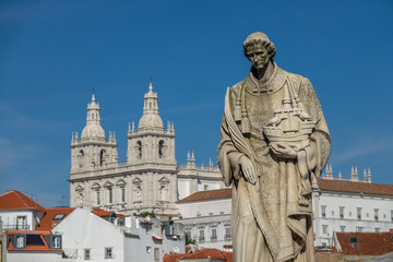 Fototapeta na wymiar Sculpture of Sao Vicente St. Vincent of Saragossa, with Igreja de Sao Vicente de Fora in the Background. Lisbon. Portugal