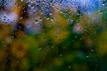 Drops Of Rain On Blue Glass Background. Street Bokeh Lights Out Of Focus. Autumn Abstract Backdrop