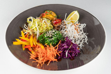 Oriental salad, disassembled into parts with wakame seaweed, bell pepper, red and green cabbage, grated carrot and smoked salmon isolated on white background