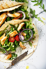 Unwrapped tortilla with fresh salad and roasted chicken and a bowl of sauce. Top view shot. Gourmet conception.