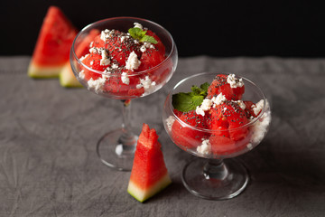 A delicious dessert of watermelon and cream cheese, decorated with a leaf of mint and chia seeds. In a glass dish