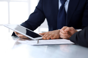 Business people using tablet computer while working together at the desk in modern office. Unknown businessman or male entrepreneur with colleague at workplace. Teamwork and partnership concept