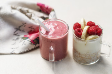 Banana, raspberry, oatmeal yogurt smoothies and ingredients in two glass cups