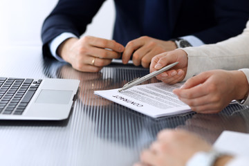 Obraz premium Business people discussing contract working together at meeting at the glass desk in modern office. Unknown businessman and woman with colleagues or lawyers at negotiation. Teamwork and partnership