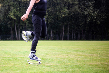 Girls in boots for jumping. Bouncing shoes on the legs of women. Sports performance on the football field in the rain. A new sport is jumping in special shoes on springs.