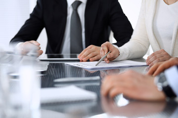 Business people discussing contract working together at meeting at the glass desk in modern office. Unknown businessman and woman with colleagues or lawyers at negotiation. Teamwork and partnership